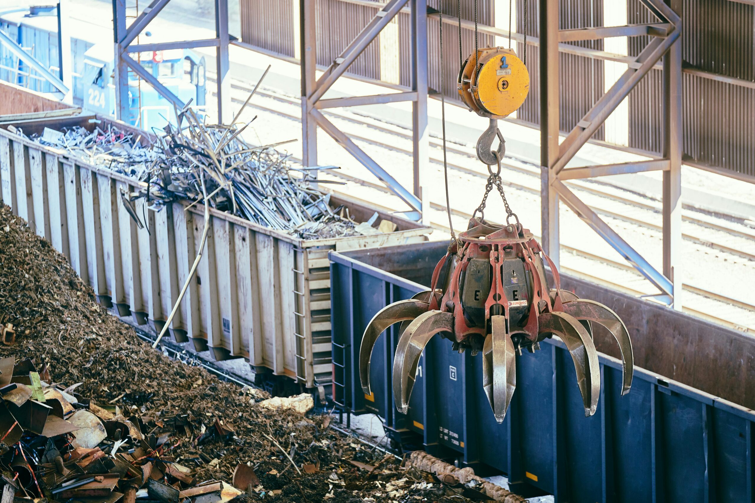 Overhead crane sorting scrap metal in an industrial recycling facility.